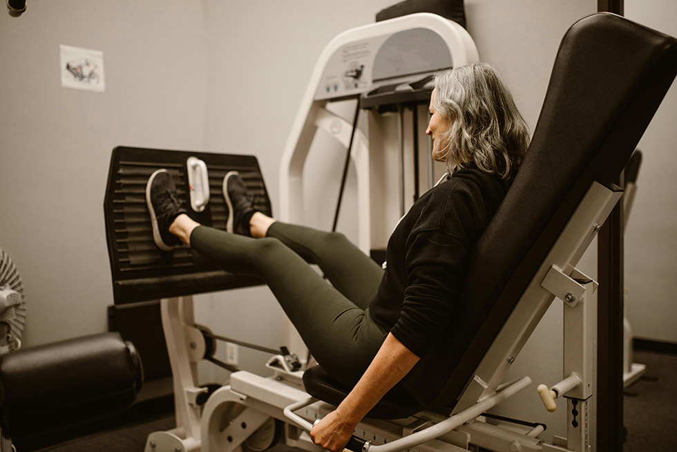 senior woman on leg machine at gym